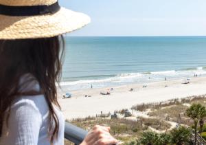 a woman in a straw hat looking at the beach at Surfside Beach Oceanfront Hotel in Myrtle Beach