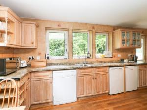 a kitchen with wooden cabinets and white appliances at Bridgedown House in Richmond