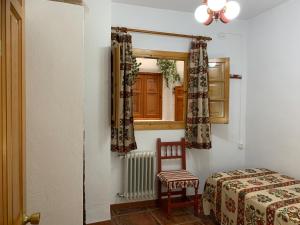 ein Schlafzimmer mit einem Bett, einem Stuhl und einem Fenster in der Unterkunft Hostal Atalaya en Capileira CB in Capileira