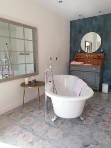 y baño con bañera, lavabo y espejo. en Le 43-3 avec sauna privatif en Le Puy-en-Velay