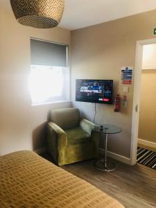 a room with a chair and a table and a tv at The Annexe II in Mildenhall