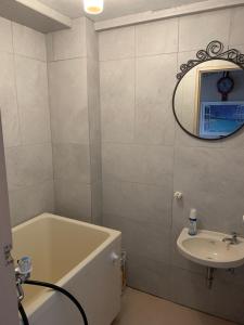 a bathroom with a tub and a sink and a mirror at Kurosaki Guesthouse 403 in Kitakyushu