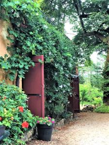 a garden with a red door and some flowers at Chambres d'hotes Les Coustilles in Saint-Alvère