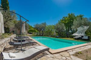 a swimming pool with chaise lounge chairs and a fountain at romantique villa provencale in Bargemon