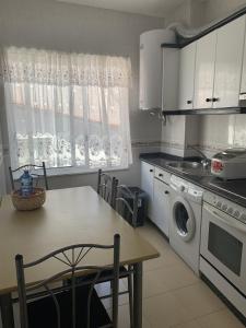 cocina con mesa y lavadora en Apartamento céntrico a 1km de la playa., en Puentedeume