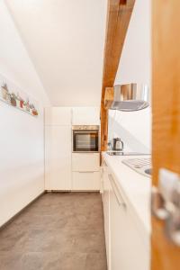 La cuisine est équipée de placards blancs et d'un four micro-ondes. dans l'établissement Urlaubsplatzl Appartements, à Oetz