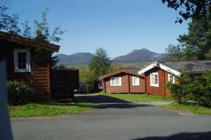 a couple of small wooden houses with mountains in the background at Cosy 2 bedroom Log Cabin in Snowdonia Cabin151 in Trawsfynydd