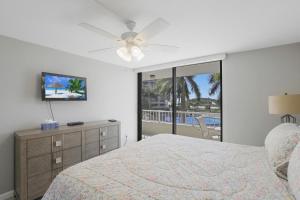 a bedroom with a bed and a ceiling fan at Ideal beachfront condo with pool and two balconies in Marco Island +37 photos
