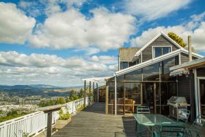 a house with a deck with a table and chairs at Aorangi Mountain Lodge in Rotorua