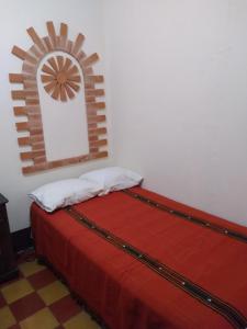 a bed with a red blanket and a mirror on a wall at Hotel Acatenango Inn in Antigua Guatemala