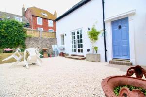 un patio con una puerta azul y una casa blanca en Betern Place By Air Premier en Seaford