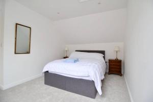 a white bedroom with a bed and a mirror at Betern Place By Air Premier in Seaford