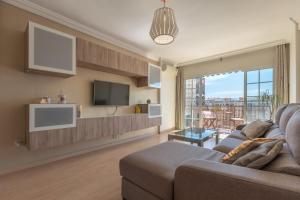ein Wohnzimmer mit einem Sofa und einem TV in der Unterkunft Apartamento de 3 habitaciones en el barrio de las Artes, Soho in Málaga