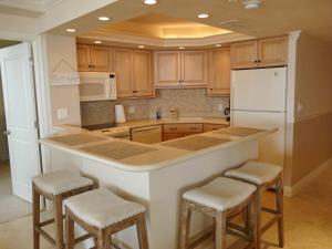 a kitchen with wooden cabinets and a white refrigerator and stools at Sandcastle I-101 in Marco Island
