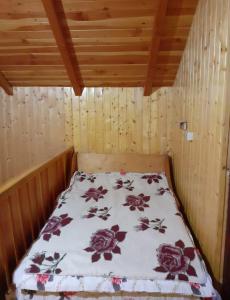 a bed in a wooden room with a blanket on it at Cabana Roșia in Roşia