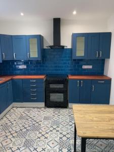 a kitchen with blue cabinets and a tile floor at LFC Staycation in Liverpool