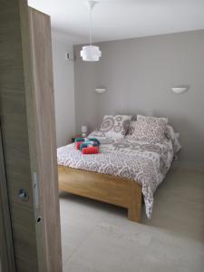 a bedroom with a bed with a white and gray comforter at LA MASTRONA in Saumane-de-Vaucluse