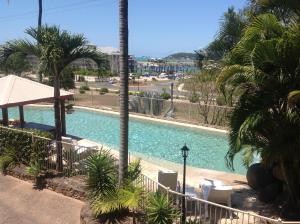 a view of a swimming pool with palm trees at at Boathaven Bay Holiday Apartments in Airlie Beach