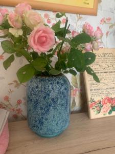 a blue vase with pink roses sitting on a table at Happy rooms in Ventspils