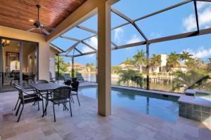Un patio con mesa y sillas y una piscina. en Waterfront home with pool, spa and outdoor kitchen, en Marco Island