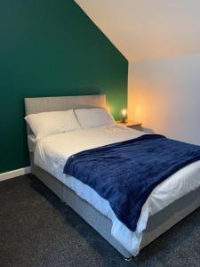 a bedroom with a large bed with a green wall at LFC Staycation in Liverpool