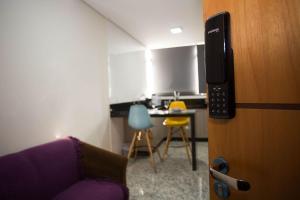 a living room with a purple couch and a kitchen at Lockings Lourdes 4 in Belo Horizonte