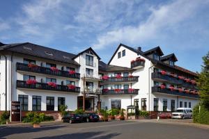 a large white building with balconies and cars parked in a parking lot at Sonnenhof in Dietzenbach