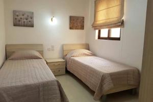 a bedroom with two beds and a window at Munxar Holiday Apartment in Marsaskala