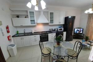 a kitchen with a table with chairs and a black refrigerator at Munxar Holiday Apartment in Marsaskala