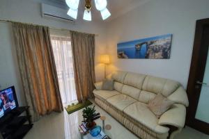 a living room with a couch and a tv at Munxar Holiday Apartment in Marsaskala