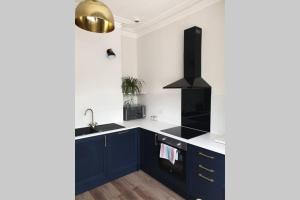 uma cozinha com armários azuis e uma pia em The Cube at No. 21. Modern & Stylish getaway. em Ilfracombe