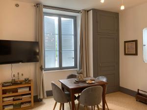 een woonkamer met een tafel en stoelen en een televisie bij La Cour Pavée, T2 lumineux, cosy, confort 55 m2 in Saint-Léonard-de-Noblat
