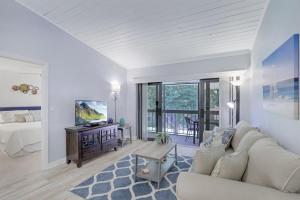 a living room with a couch and a tv and a bed at Charming condo with two pools and steps to beach in Marco Island