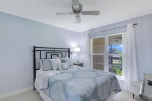 a bedroom with a bed with a ceiling fan and a window at Charming condo with two pools and steps to beach in Marco Island +22 photos