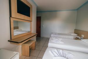 a hotel room with two beds and a mirror at Hotel Triângulo in Caldas Novas