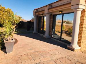 uma casa com grandes janelas e um vaso de plantas em Nimza K Guesthouse em Kimberley