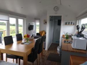 a dining room and living room with a table and chairs at Cleeves Cabins Arran Luxury Lodge with hot tub in Dalry