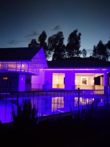Una casa con luces moradas en la parte delantera. en Rancho California, en Pitalito