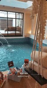 a large swimming pool with a bed in a room at شاليه كاردڤ1 in Al Baha