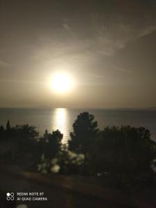 a sun setting over the ocean with trees in the foreground at Marechiaro Home Holiday in Vico Equense