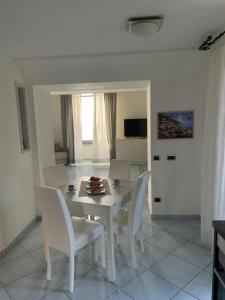 een witte eetkamer met een tafel en stoelen bij Marechiaro Home Holiday in Vico Equense