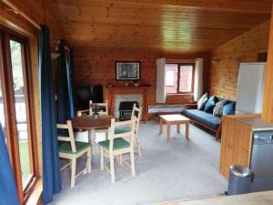 - un salon avec une table, des chaises et un canapé dans l'établissement Wooden Forest Lodge by the sea, à Milford on Sea