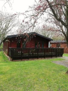 a house with a wooden fence in front of it at Wooden Forest Lodge by the sea in Milford on Sea