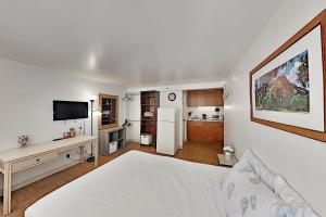 a bedroom with a white bed and a kitchen at Hawaiian Monarch 801 condo in Honolulu