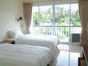 a hotel room with two beds and a large window at Choengmon Residence in Choeng Mon Beach