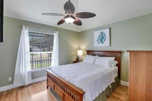 a bedroom with a bed with a ceiling fan and a window at Waterfront home with pool and foosball table in Marco Island +42 photos