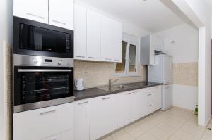 a white kitchen with a sink and a microwave at Villa Bepo in Plano