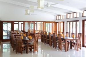 a dining room with wooden tables and chairs and windows at The Lakeside at Nuwarawewa in Anuradhapura