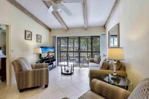 a living room with a couch and chairs and a tv at Inland condo with pool and steps to beach/food/shops in Marco Island