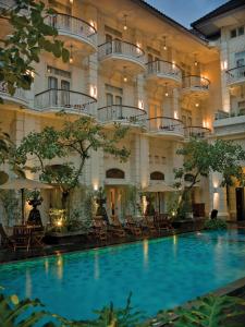 a large building with a large swimming pool in front of it at The Phoenix Hotel Yogyakarta - MGallery Collection in Yogyakarta